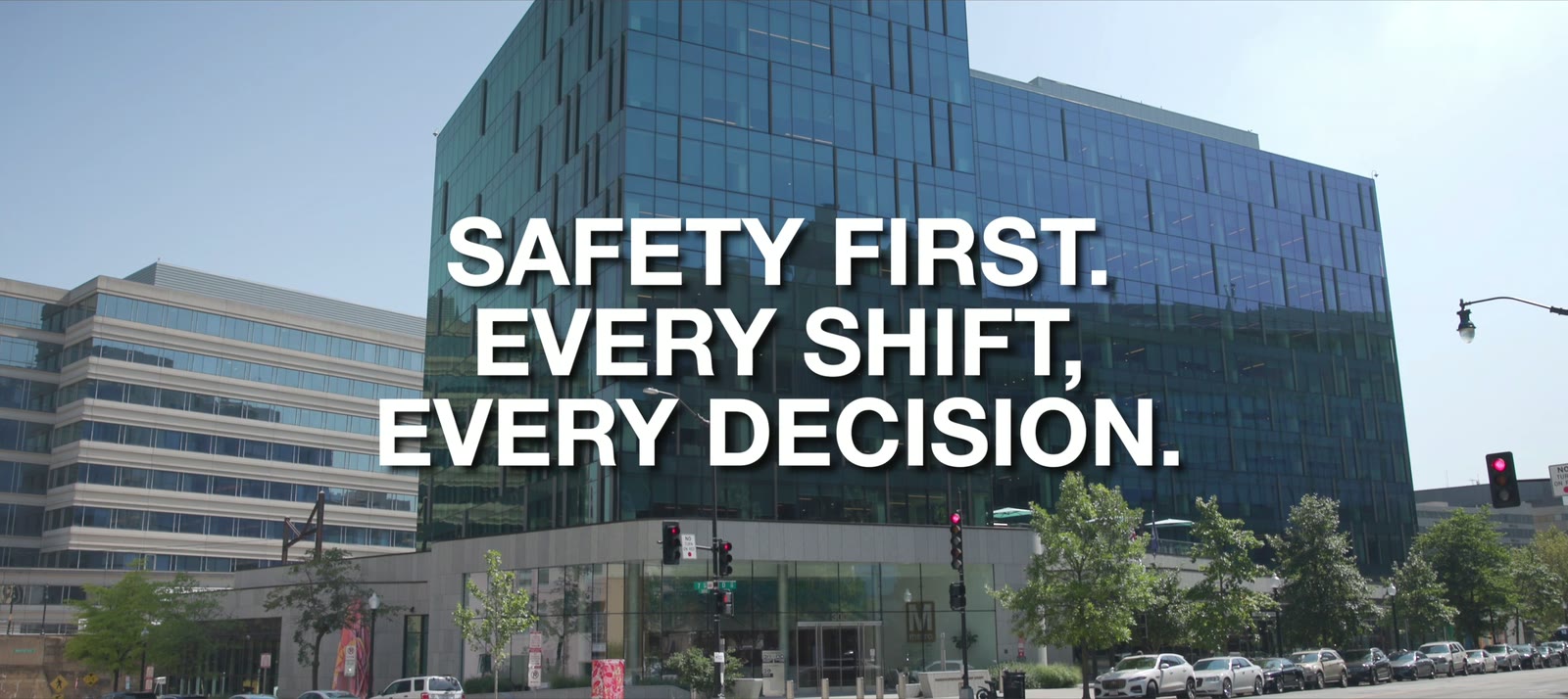 Title card reading "Safety First. Every Shift, Every Decision." over a glass office building on a city street.