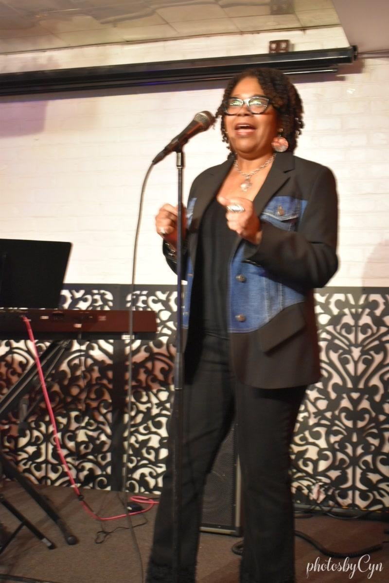 Renita Martin performing at a microphone beside a keyboard.